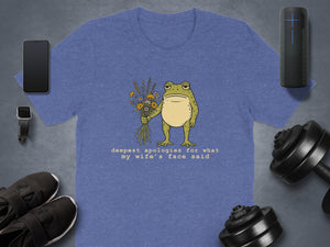 Blue t-shirt with drawing of frog holding flowers and text saying "deepest apologies for what my wife's face said".