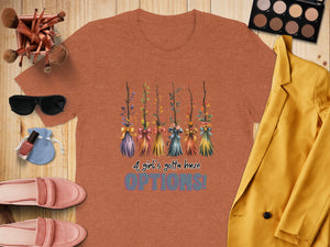 Orange t-shirt with colorful broomsticks and the text "A girl's gotta have OPTIONS!".
