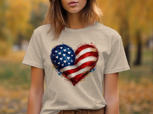 Light tan t-shirt with American flag heart graphic and a blurred autumn background.