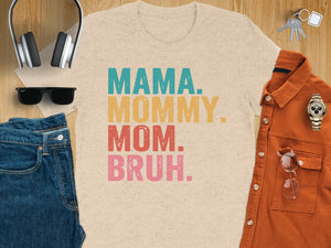 T-shirt with "Mama. Mommy. Mom. Bruh." text and accessories on a wooden surface.