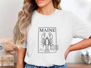 White t-shirt with a black outlined lobster stamp featuring "MAINE", "NEW ENGLAND", and "U.S.A."