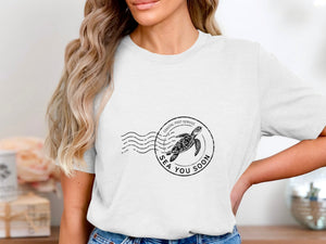 T-shirt with black circular stamp featuring a sea turtle and "SEA YOU SOON."