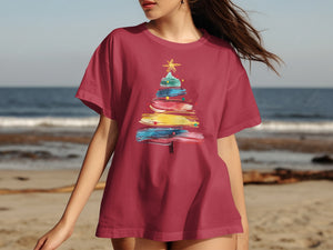 Maroon t-shirt with colorful abstract Christmas tree graphic on a beach background.