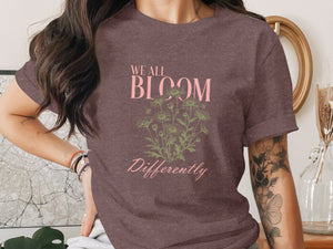 Brown t-shirt with "We All Bloom Differently" text and floral graphic.