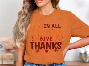 Orange t-shirt with text "In All Things Give Thanks" and pumpkins.