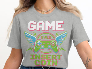 Grey t-shirt with pixel art "GAME OVER INSERT COIN" and controller with wings.