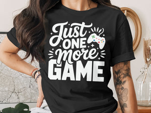 Black t-shirt with white text "Just ONE more GAME" and a game controller graphic.
