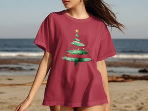 Woman wearing a maroon t-shirt with a green Christmas tree graphic.