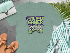 Green t-shirt with pixelated "GAME OVER GAMER" text and a retro video game controller.
