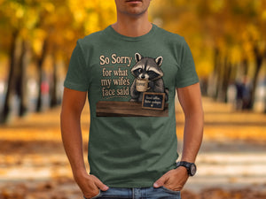 Green t-shirt with raccoon holding coffee, text "So Sorry for what my wife's face said."