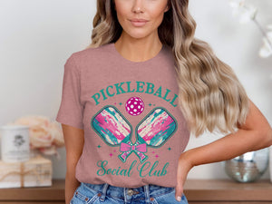 Pickleball Social Club text with pickleball paddles and ball graphic on a pink t-shirt.