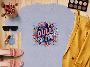 Light gray t-shirt with "Never Let Anyone Dull Your Sparkle" graphic and surrounding accessories.
