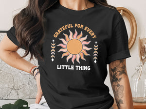 Black t-shirt with "Grateful for Every Little Thing" text and sun graphic.