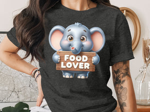 Cute cartoon elephant holding a "FOOD LOVER" sign on a dark t-shirt.