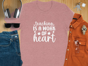 Pink t-shirt with white text "teaching is a work of heart" and apples.