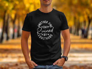 Black t-shirt with white text that reads "Another fine day ruined by adulthood".