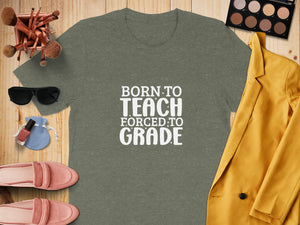 Green t-shirt with "Born To Teach Forced To Grade" slogan and various accessories.