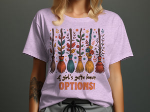 T-shirt with brooms, leaves, flowers, and text "A girl's gotta have OPTIONS!"