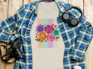 Light gray t-shirt on wooden surface with floral design and open plaid shirt.