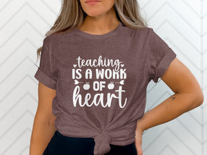 Brown t-shirt with white text "teaching IS A WORK OF heart" and apple graphics