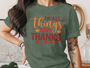 Green t-shirt with "In All Things Give Thanks" text and pumpkin graphics.