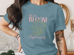 Blue t-shirt with "WE ALL BLOOM Differently" text and floral graphic.