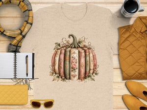 T-shirt with vintage book pumpkin graphic, surrounded by autumn accessories.