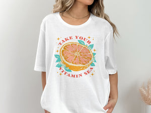 White graphic t-shirt with a grapefruit slice illustration and the text "TAKE YOUR VITAMIN SEA".