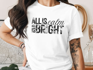 White t-shirt with "All is calm, all is bright" text and a candle graphic.