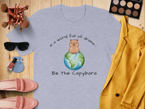 Light grey t-shirt with a capybara on a globe and text "In a world full of drama... Be The Capybara".
