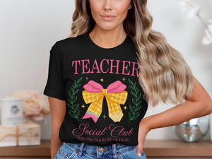 Black t-shirt with pink text reading "TEACHER SOCIAL CLUB" and a graphic of a bow with a pencil.