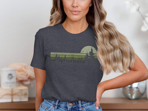 Dark grey t-shirt with a green retro forest and sun graphic.