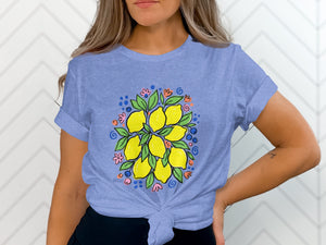 Blue t-shirt with a central illustration of lemons, leaves, and colorful dots and flowers.
