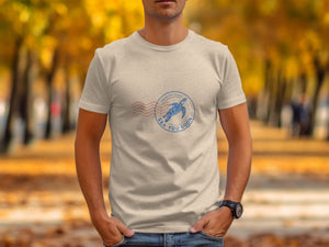 T-shirt with a blue stamp featuring a sea turtle and "SEA YOU SOON" text.