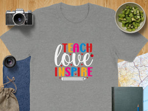 Grey t-shirt with "Teach Love Inspire" text and a pencil graphic.
