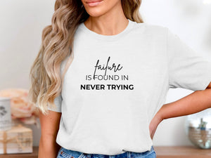 White t-shirt with the text "failure is found in never trying" in black font.