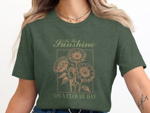 Green t-shirt with "Be the Sunshine On A Cloudy Day" and sunflower graphic.