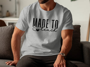 Grey t-shirt with black text "MADE TO teach" and a small heart.