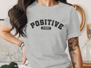 Grey t-shirt with "POSITIVE VIBES" text in distressed black lettering.