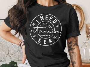 Black t-shirt with a circular white graphic reading "I NEED Vitamin SEA"