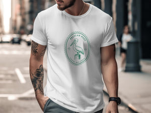 White t-shirt with a green circular logo featuring a pelican and "Pelican Post Coastal Mail Service 1987".