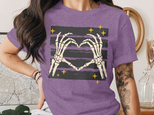 Skeleton hands forming a heart on a purple t-shirt with stars.