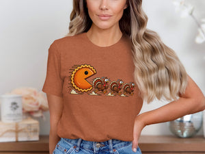 Pie-shaped Pac-Man character chases three cartoon turkeys across t-shirt.