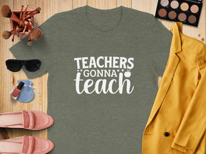 Olive green t-shirt with white text "Teachers Gonna Teach" on wooden background.