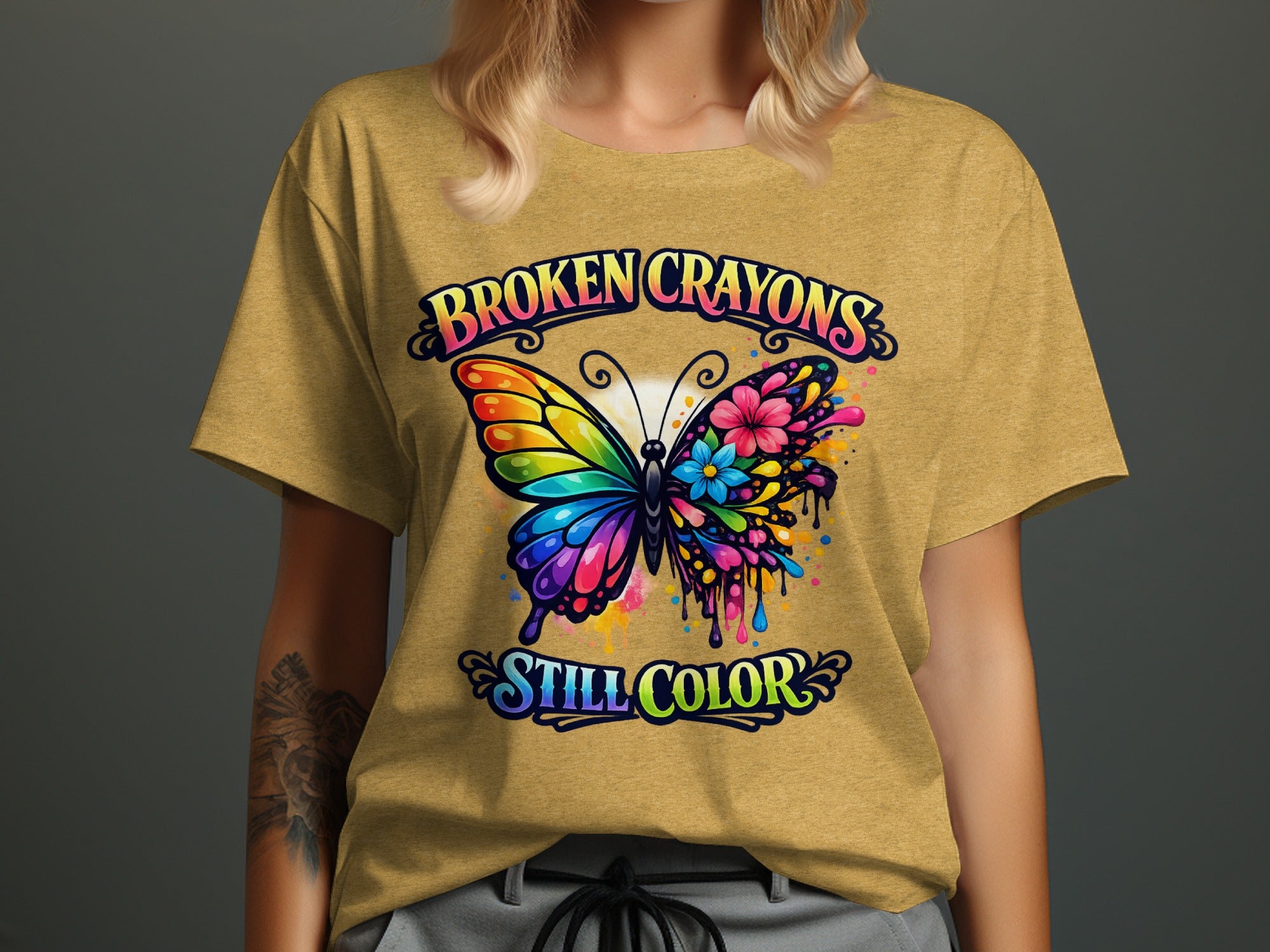 Yellow t-shirt graphic with colorful butterfly and text "BROKEN CRAYONS STILL COLOR".