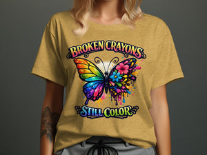 Yellow t-shirt graphic with colorful butterfly and text "BROKEN CRAYONS STILL COLOR".