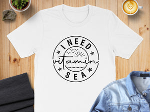 White t-shirt with "I need vitamin sea" text and beach illustration.
