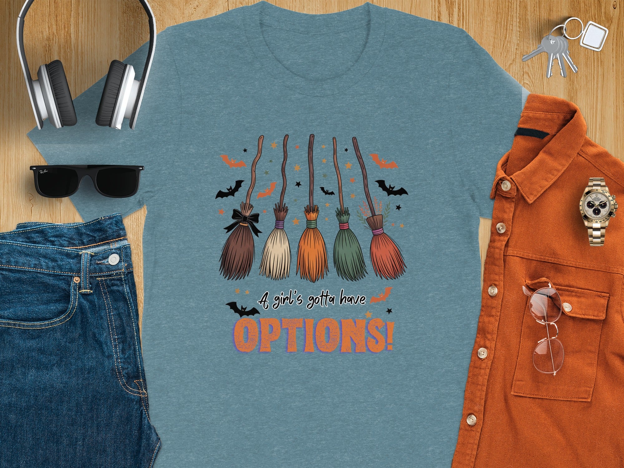 Blue t-shirt with five broomsticks, bats, stars, and text "A girl's gotta have OPTIONS!".