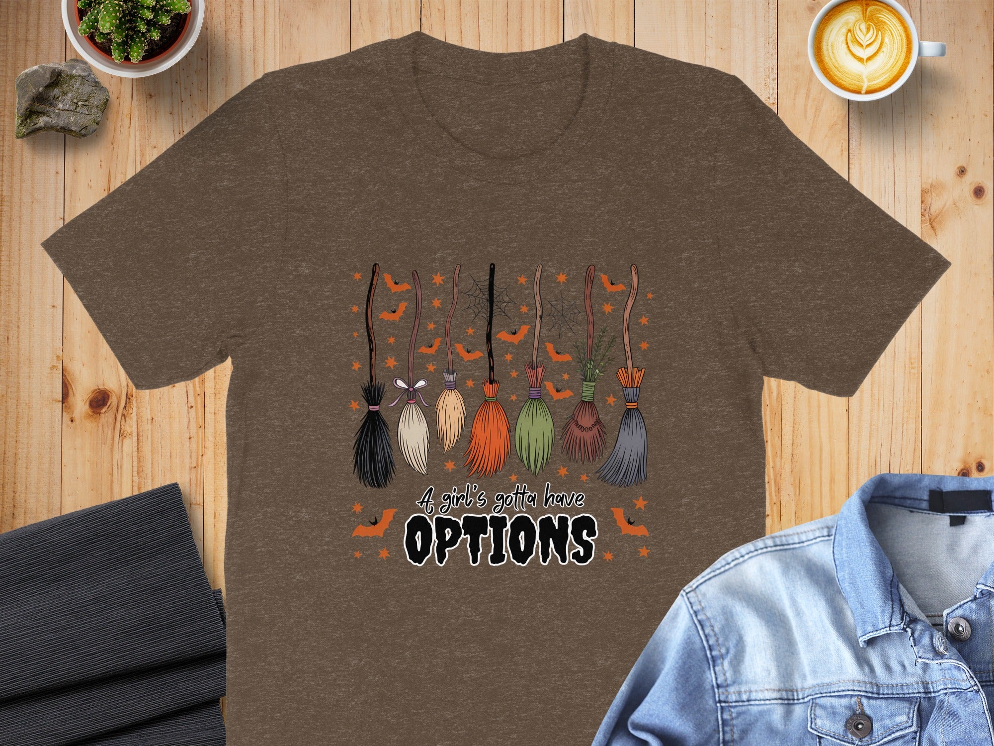 Brown t-shirt with Halloween illustration of brooms, bats, and text "A girl's gotta have OPTIONS".