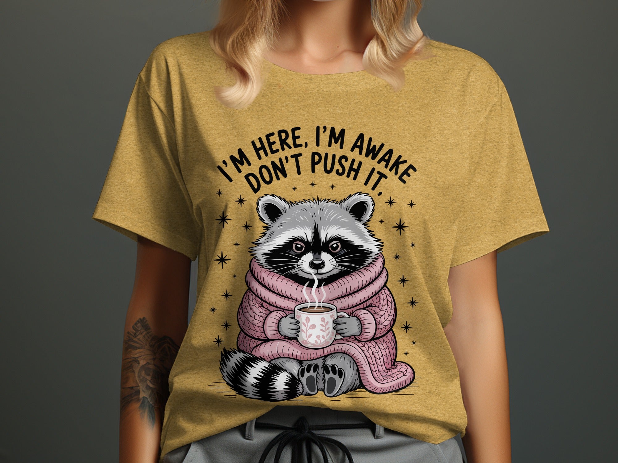 Raccoon wearing pink scarf holds coffee mug with text "I'M HERE, I'M AWAKE, DON'T PUSH IT."